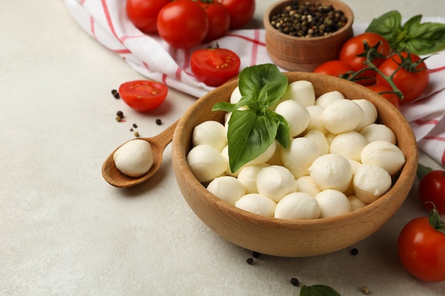 Conceito de comer saboroso com uma tigela de queijo mussarela no fundo branco texturizado