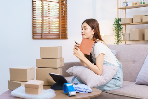 Conceito de comerciante online Empresário feminino relaxa depois de embalar o produto em caixas de encomendas