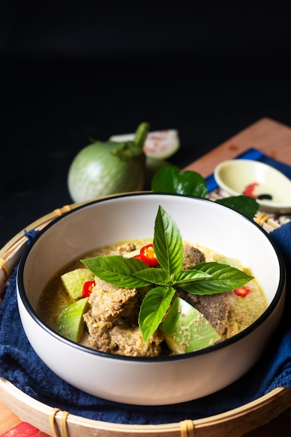 Foto conceito de comida asiática autêntica carne de curry verde tailandês e berinjela verde tailandesa na placa de madeira com espaço de cópia