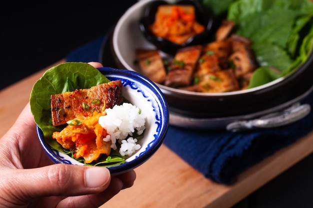 Conceito de comida asiática caseiro barriga de porco grelhada coreana bbq samgyeopsalgui com kimchi e shiso e salada em fundo preto com espaço de cópia