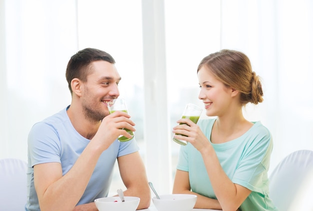 conceito de comida, casa, casal e felicidade - casal sorridente tomando café da manhã em casa