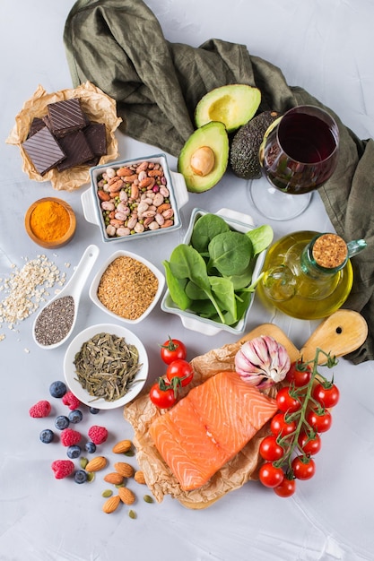 Foto conceito de comida de dieta equilibrada variedade de alimentos saudáveis espinafre baixo colesterol abacate vinho tinto chá verde salmão tomate bagas linho sementes de chia açafrão alho nozes azeite vista superior