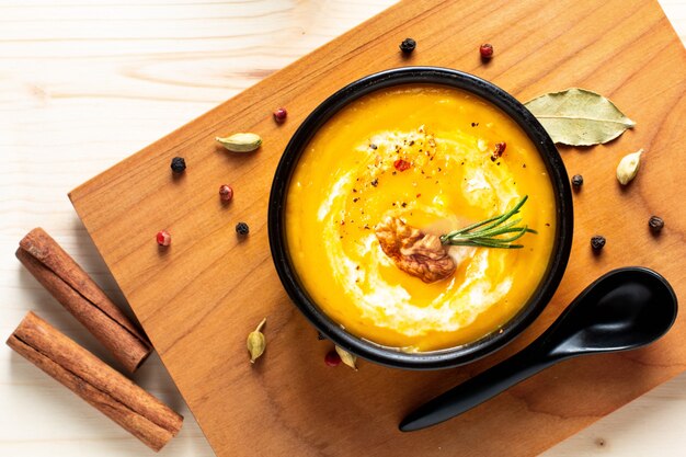 Conceito de comida de outono inverno Sopa de abóbora ou butternut em tigela preta sobre fundo de madeira