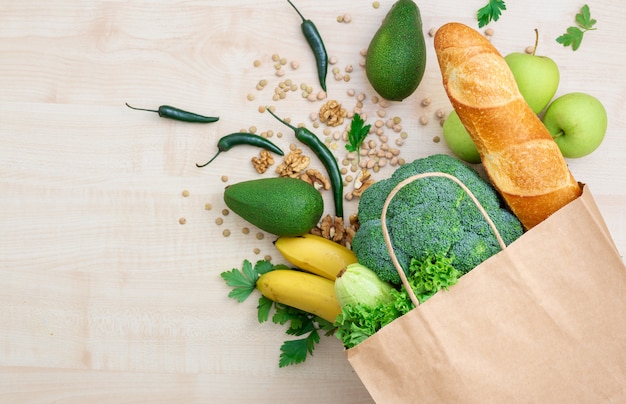 Foto conceito de comida de saco. compras compras saco de papel com alimentos saudáveis em uma vista superior de madeira