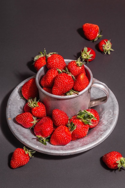 Conceito de comida de verão com um morango em um fundo de pedra preta. Bagas maduras aromáticas, luz dura moderna, sombra escura, espaço de cópia