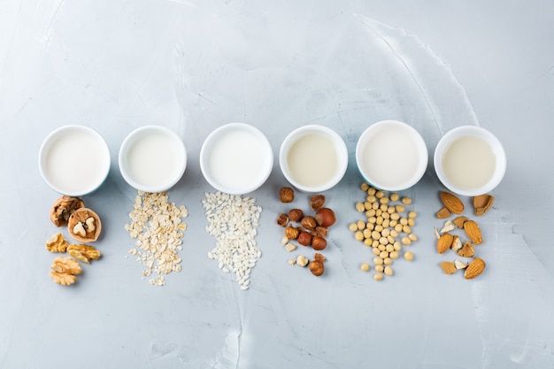 Conceito de comida e bebida, cuidados de saúde, dieta e nutrição. Variedade de leite não lácteo vegan orgânico de nozes em copos na mesa da cozinha. Vista superior do plano de fundo