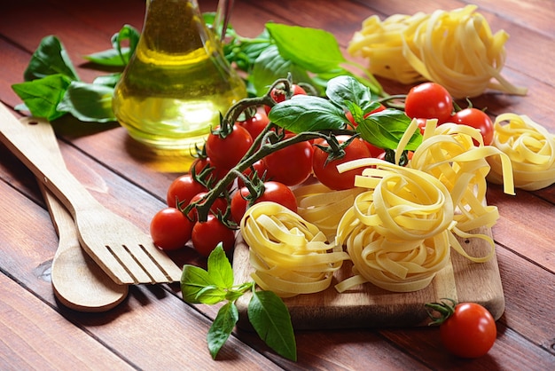 Conceito de comida italiana com massa crua, tomate, manjericão e azeite