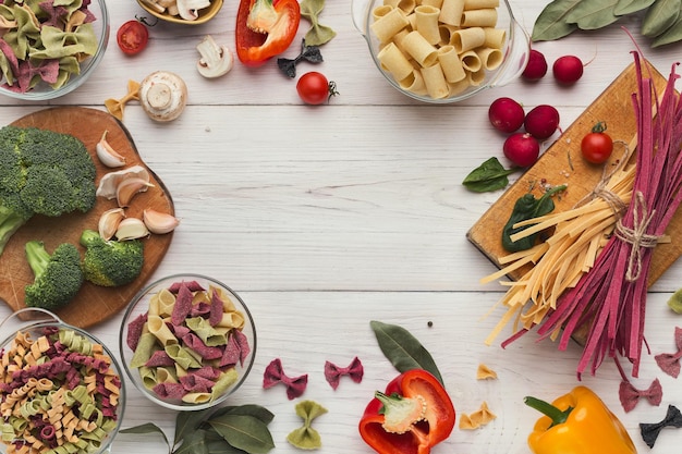 Conceito de comida italiana. variedade de massas e vegetais coloridos secos em madeira branca. moldura para espaço de cópia, vista superior, configuração plana