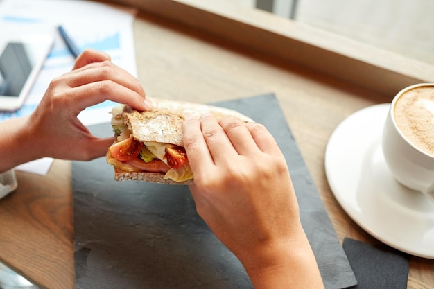 conceito de comida, jantar e pessoas - mulher comendo sanduíche de panini de salmão com tomate e queijo no restaurante