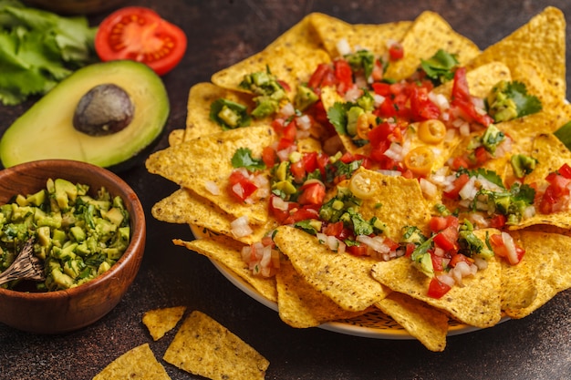 Foto conceito de comida mexicana. nachos - chips de milho amarelo totopos com vários molhos em tigelas de madeira: guacamole, molho de queijo, pico del gallo