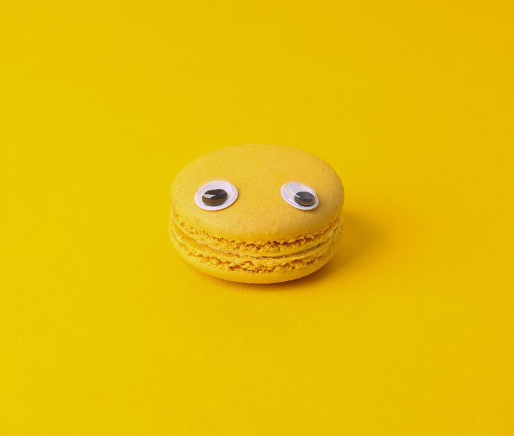 Foto conceito de comida mínima macarão francês amarelo com olhos em fundo amarelo