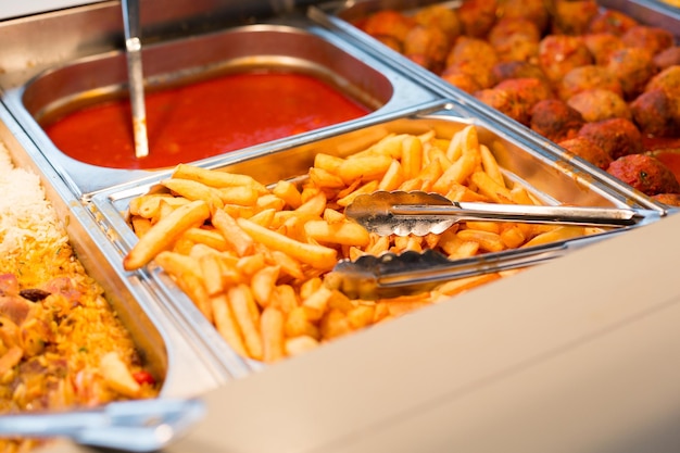 conceito de comida, restauração, autoatendimento e alimentação - close-up de batatas fritas e outros pratos na bandeja metálica