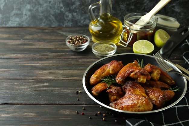 Conceito de comida saborosa com asas de frango assadas em fundo de madeira, espaço para texto