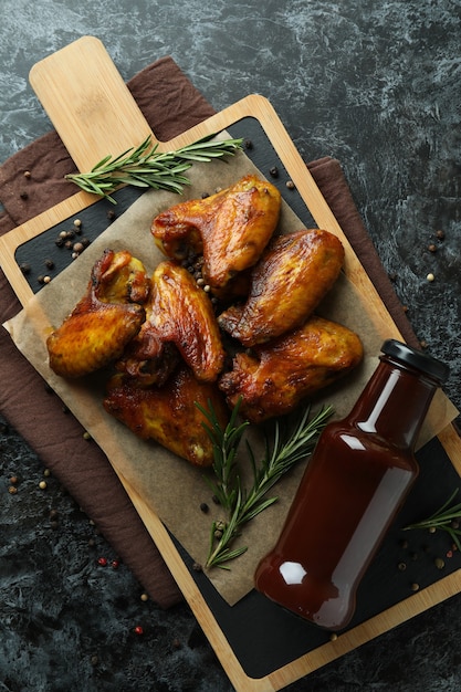 Conceito de comida saborosa com asas de frango assadas em fundo preto esfumaçado