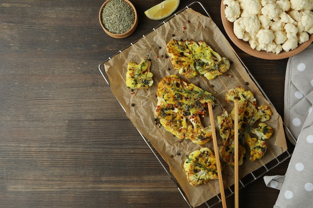 Conceito de comida saborosa com couve-flor assada em fundo de madeira.