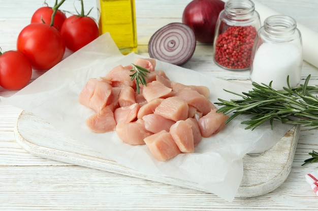 Conceito de comida saborosa com fatias de filé de frango cru em fundo branco de madeira