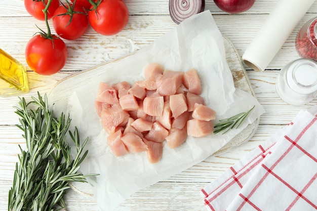 Conceito de comida saborosa com fatias de filé de frango cru em fundo branco de madeira