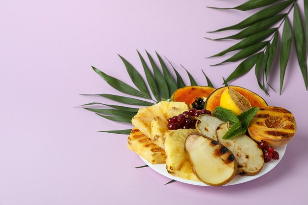 Conceito de comida saborosa com frutas grelhadas em fundo violeta.