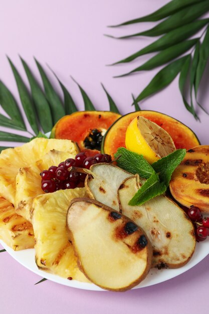 Foto conceito de comida saborosa com frutas grelhadas em fundo violeta.