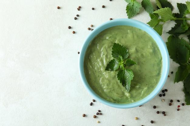 Conceito de comida saudável com sopa de urtiga na mesa texturizada branca