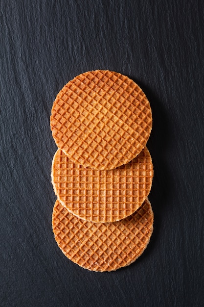 Conceito de comida Stroopwafel, xarope de caramelo crocante waffles holandeses em pedra ardósia preta