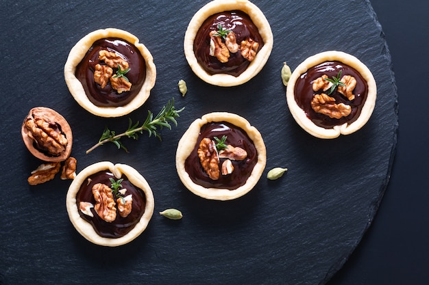 Conceito de comida tortas de mini chocolate e nozes orgânicas rústicas caseiras na placa de pedra ardósia preta com espaço de cópia