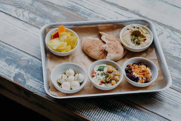 Conceito de comida tradicional de Israel Tigela de prato exótico na bandeja Hummus legumes com especiarias Pão pita Delicioso café da manhã Queijo de cabra