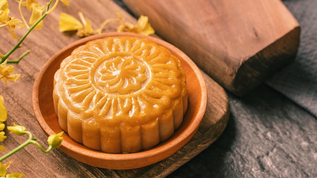 Conceito de comida tradicional do Festival MidAutumn Bolo de lua bonita na mesa de ardósia preta com flor de molde de pastelaria de chá fechar espaço de cópia