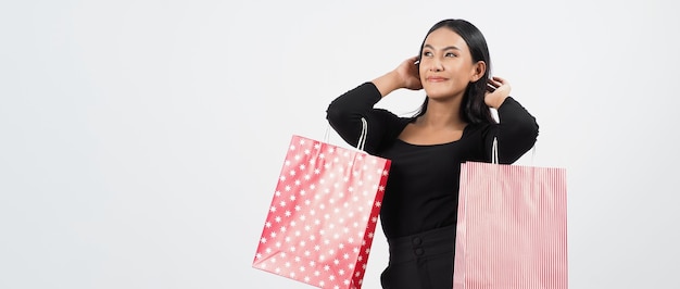 Conceito de compra de mulher. Felizmente menina e sacolas de compras durante a temporada de vendas. Feliz jovem asiática tailandesa em ação ou atividade de compra de mercadorias em lojas ou loja online e fundo branco.