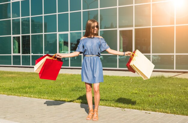 Conceito de compra, desconto e pessoas - retrato de uma jovem mulher vestida, andando com sacolas coloridas.