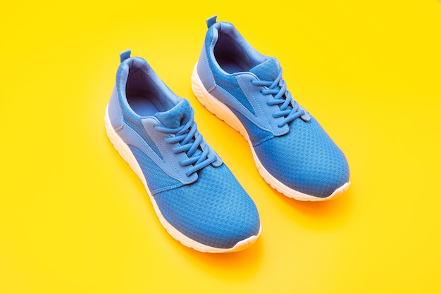 Conceito de compras. calçado para treino. calçado atlético para corrida. par de calçados esportivos confortáveis. tênis azuis esportivos. sapatos em fundo amarelo. loja de sapatos.