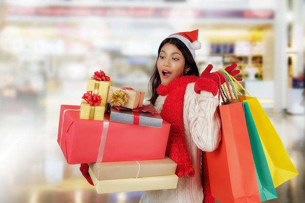 Conceito de compras. Mulher asiática que prende uma caixa de presente sobre o fundo do centro comercial.