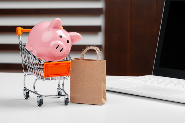 Conceito de compras on-line. Carrinho de compras, laptop na mesa