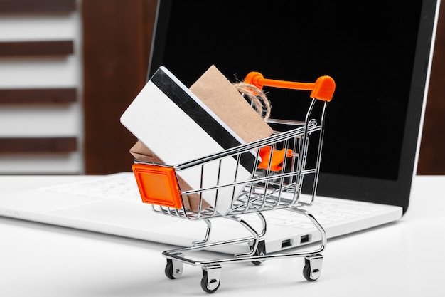 Foto conceito de compras on-line. carrinho de compras, laptop na mesa