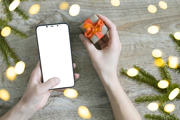 Conceito de compras online de Natal Mulher compra presentes com celular se prepara para o natal com caixa de presente na mão Vendas de férias de inverno