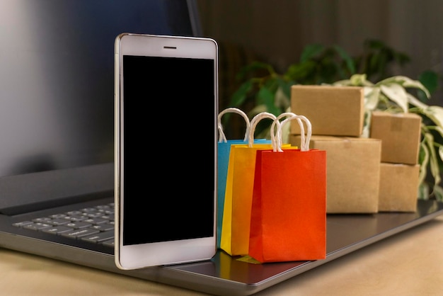 Foto conceito de compras online pequenas caixas de entrega de smartphones sacolas de compras carrinho de compras no laptop