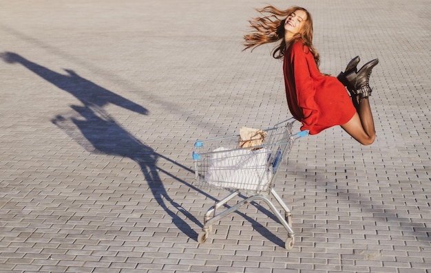 Conceito de compras Venda e desconto de consumismo Mulher feliz com carrinho de compras ao ar livre