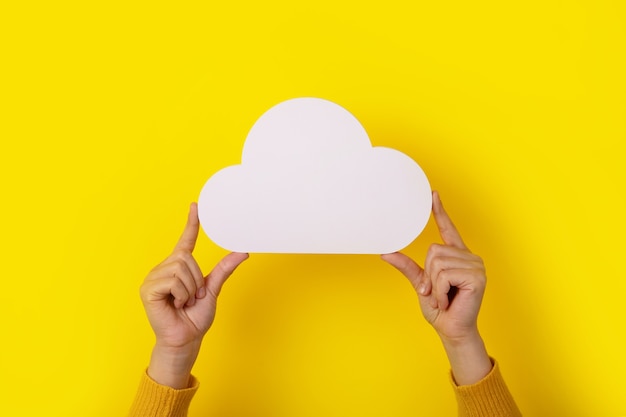 Conceito de computação em nuvem, mãos segurando uma nuvem sobre fundo amarelo, armazenamento em nuvem