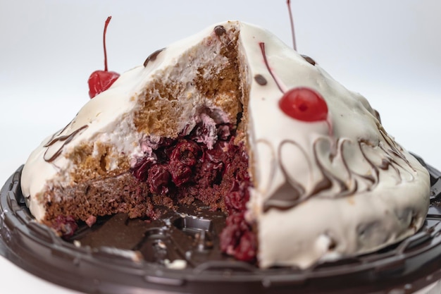 Conceito de confeitaria Bolo de cereja coberto com creme branco decorado com cereja gira sobre fundo branco