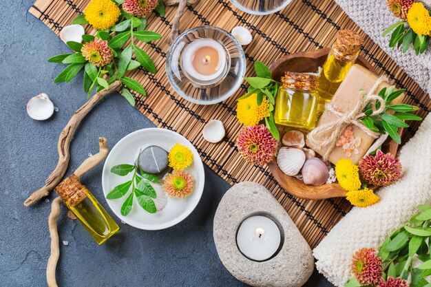 Conceito de configuração de bem-estar de outono outono spa ainda vida Variedade de creme de óleo essencial sal marinho velas de sabão natural flores laranja amarelas e toalha em uma mesa preta Vista superior plana leiga fundo