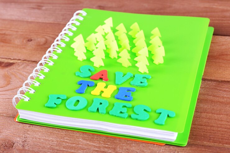 Foto conceito de conservação de florestas de papel cortado em caderno em mesa de madeira