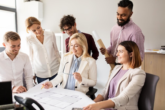 conceito de construção, construção, arquitetura, imóveis e pessoas - equipe de negócios com reunião de projeto e discussão de projeto de casa no escritório