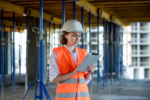 Conceito de construção de engenheiro ou arquiteto trabalhando no canteiro de obras. Uma mulher com um tablet em uma construção. Escritório de Arquitetura.