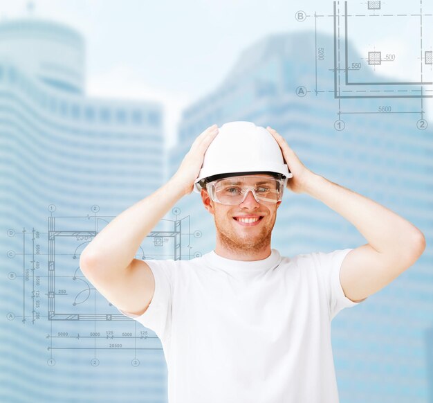 conceito de construção, desenvolvimento, consrtução e arquitetura - arquiteto masculino com capacete branco e óculos de segurança