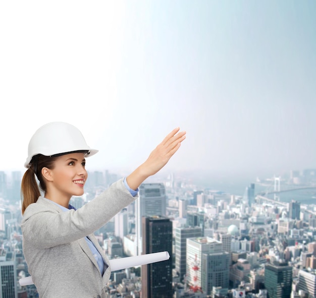 conceito de construção, desenvolvimento, construção e arquitetura - jovem e amigável arquiteto sorridente em capacete branco com plantas