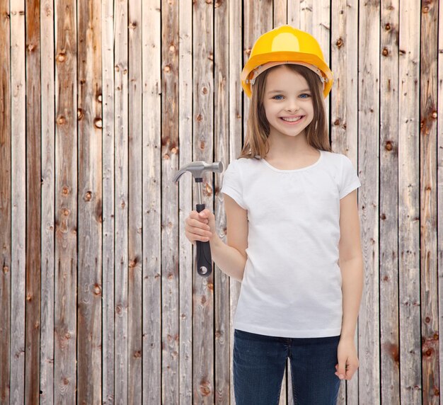 conceito de construção e pessoas - menina sorridente no capacete protetor com martelo