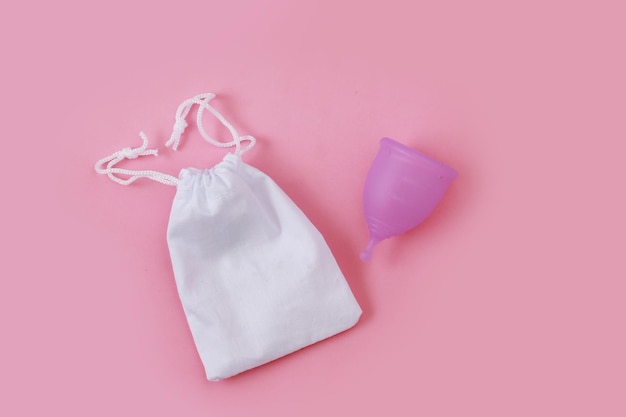 Conceito de copo menstrual de menstruação de dias críticos em fundo rosa