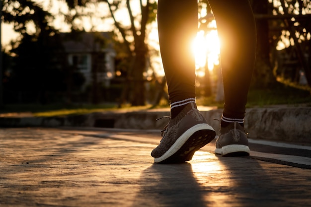 Conceito de corrida, pernas e pés de corredor use tênis de corrida ângulo baixo desde a luz de fundo da estrada até o sol