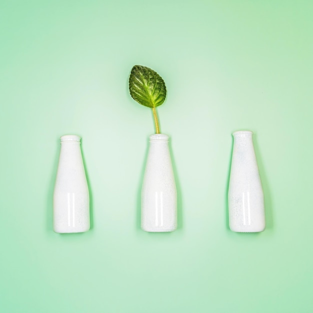 Conceito de cosmético natural com garrafas e folhas sobre fundo verde claro