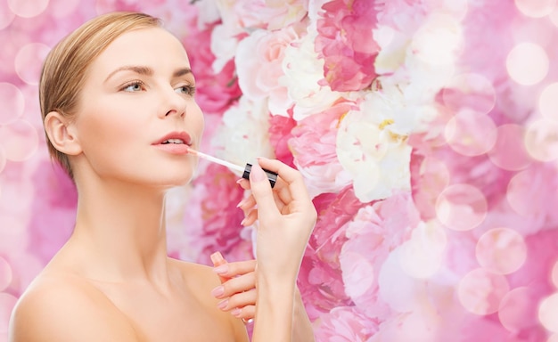 conceito de cosméticos, saúde e beleza - linda mulher com gloss rosa